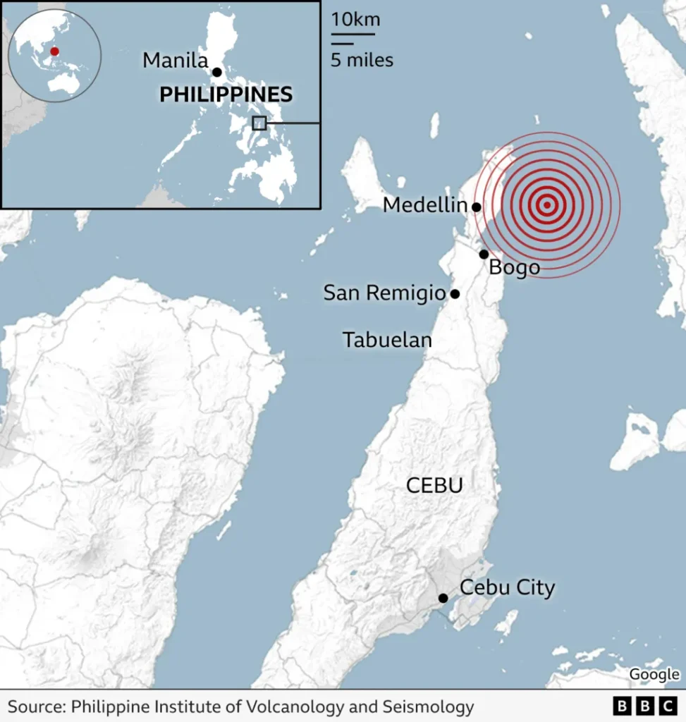 A scene of destruction in the town of Bogo, showing a collapsed concrete wall and a heavily cracked road, illustrating the powerful force of the recent Philippines earthquake.